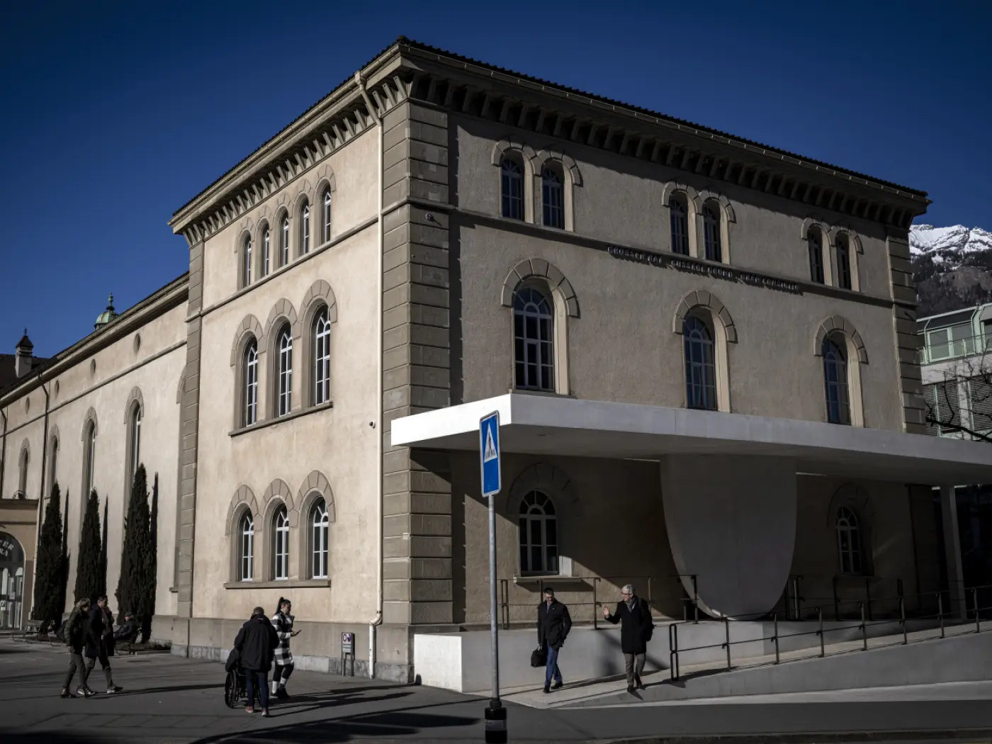 Edificio di forma angolare con finestre architettoniche, caratterizzato da un'entrata moderna e una struttura in parte contemporanea. Sullo sfondo, si intravvedono
